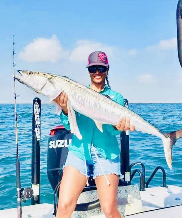 woman holding a giant fish while standing on a boat