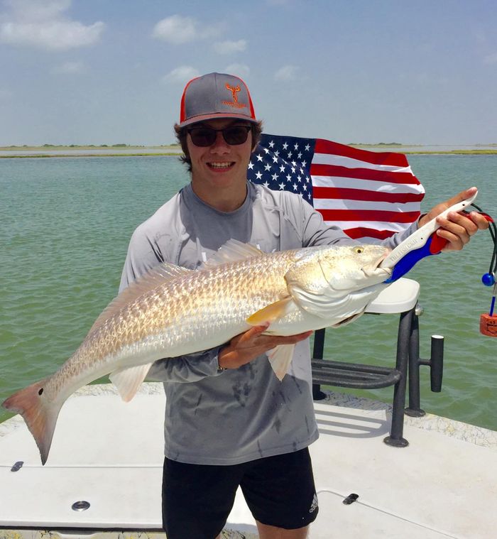  a guy holding a giant fish on a white boat