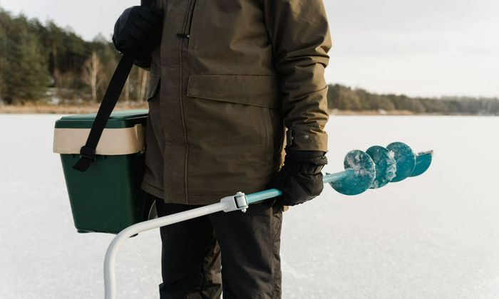 man wearing jacket holding an auger and water cooler