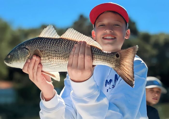 A boy holds a redfish