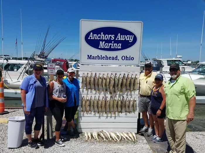 people taking a picture beside the marblehead signage with row of fish