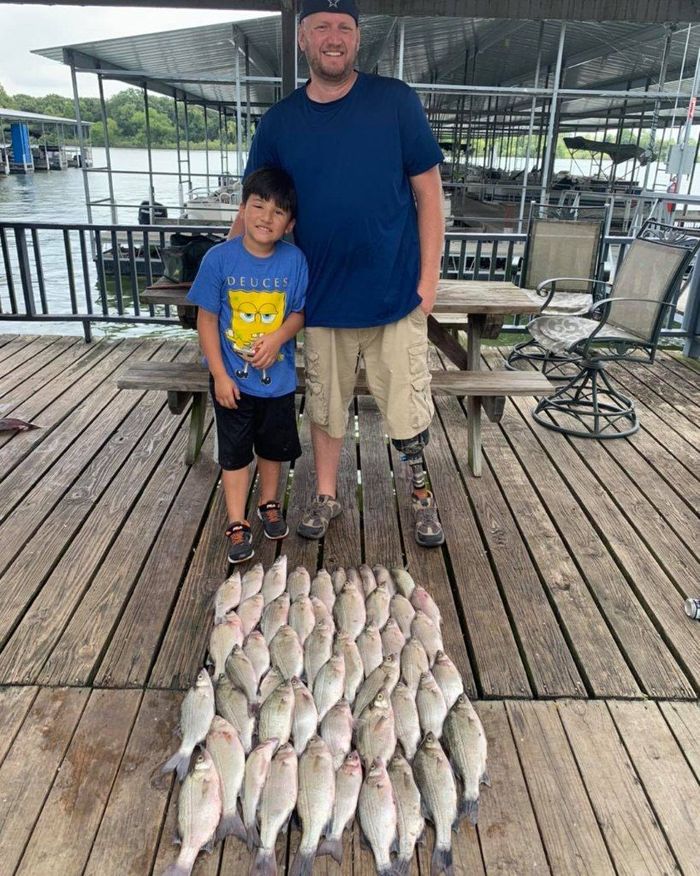 man and a kid standing in front of the row of fish