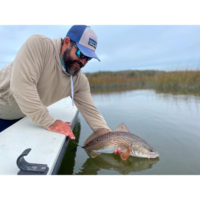 man on the edge releasing a fish on his hand