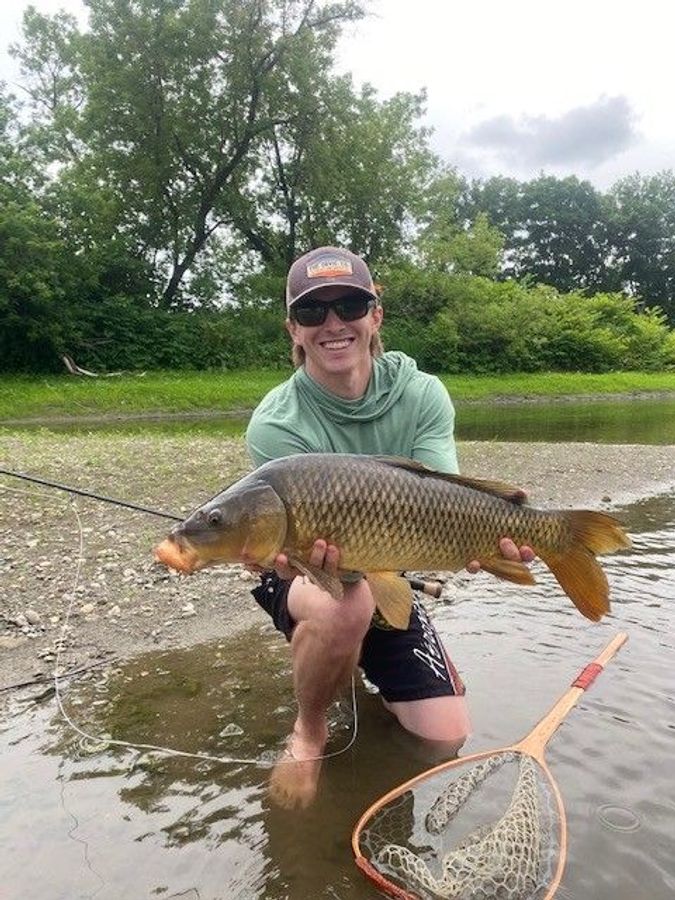 a guy happily holding a giant carp
