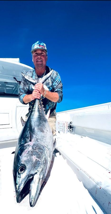 man holding a giant tuna on its tail