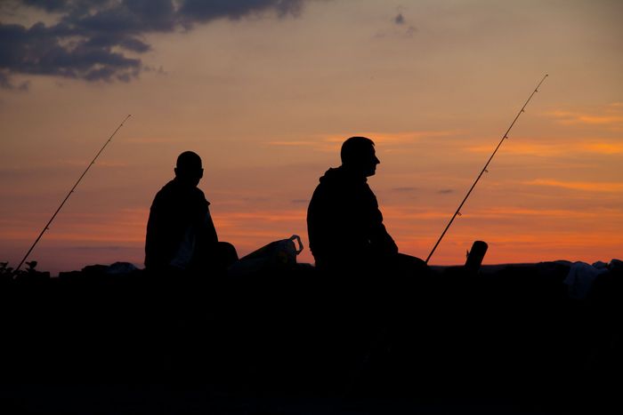 Silhouette of two men fishing at sunset 