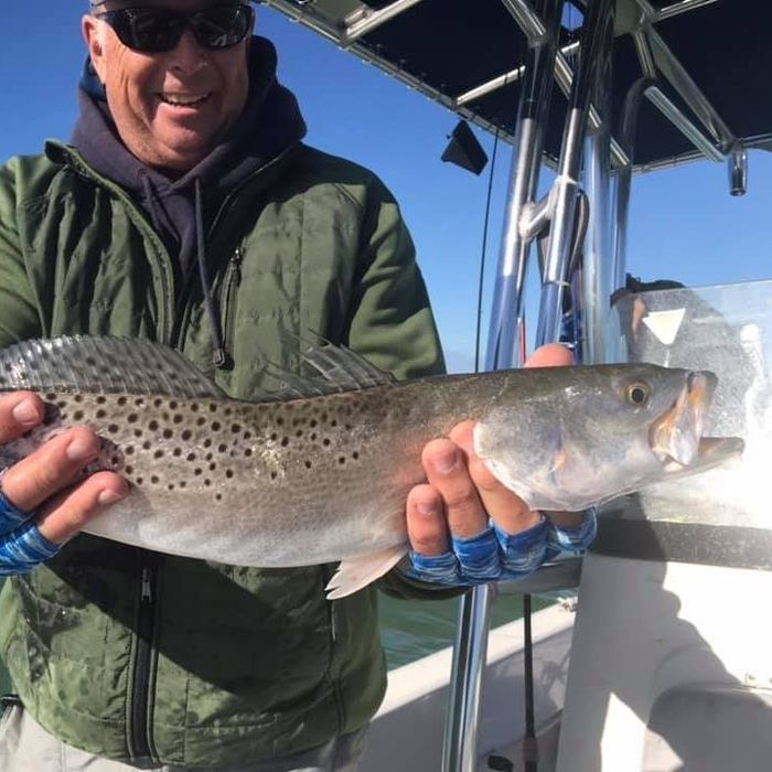 man in green jacket holding a sea trout