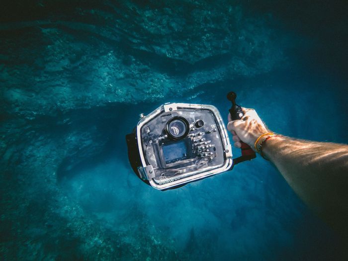 A person holding a camera underwater