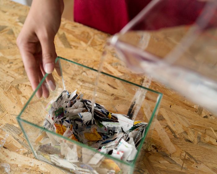 elevated-view-female-s-hand-pouring-water-pieces-paper-desk.jpg