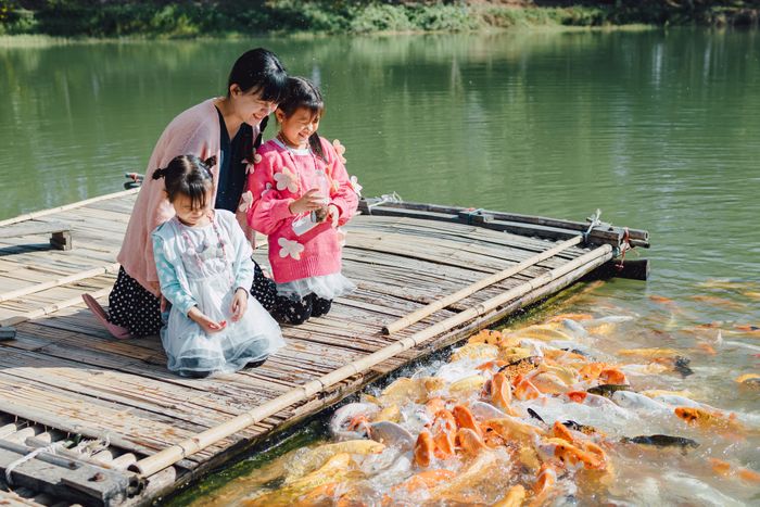 family-portrait-mother-children-feeding-fish-lake.jpg