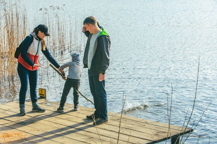 father-mother-with-boy-kid-playing-with-bench-near-water-riverside.jpg