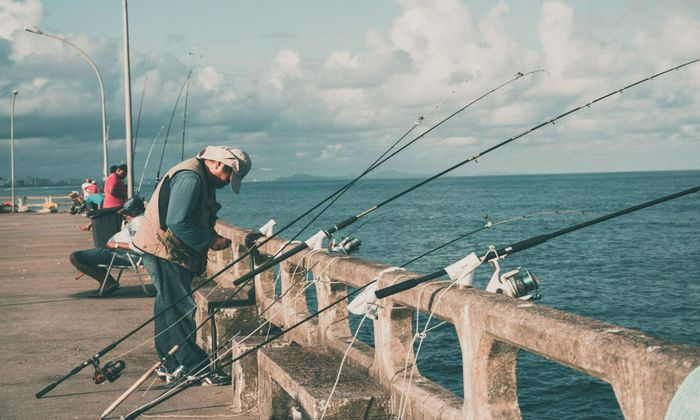 man tying fishing rods at the bridge