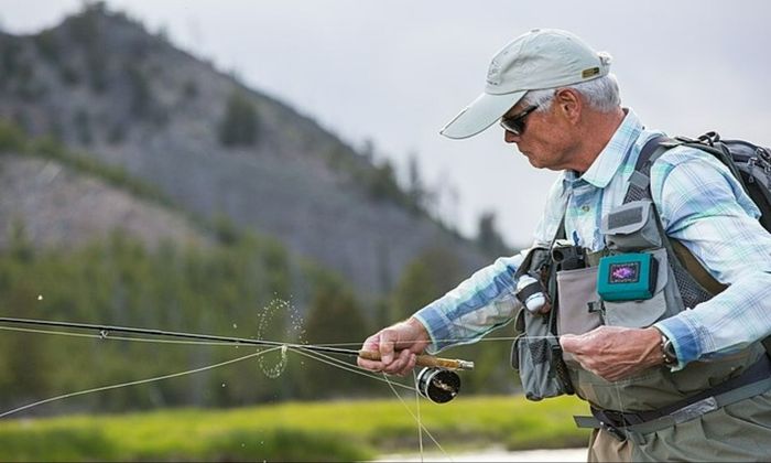 an angler holds his line as water drops a fly off the line in a circle