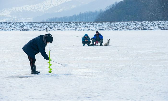 angler drilling holes in the ice