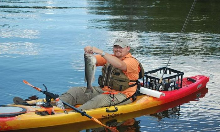 man on a kayak holding a giant fish