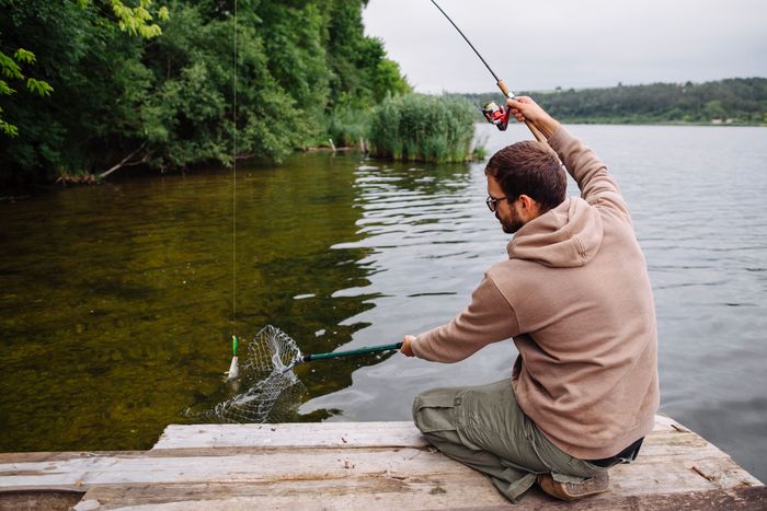man-sitting-pier-catching-fish-with-fishing-rod (2).jpg