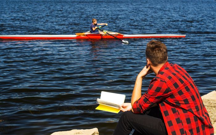 man-sitting-rock-reading-book-near-river-guy-looks-kayak (1).jpg