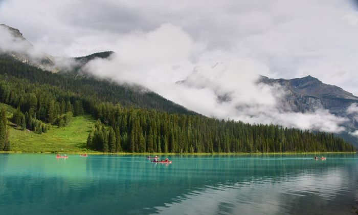 people riding a boat sailing on the green lake