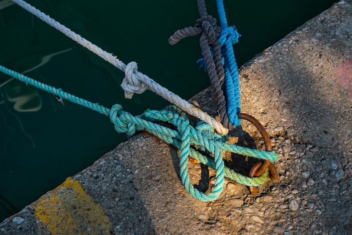 mooring-ring-with-tied-blue-white-nautical-rope-mounted-concrete-pier-marina-safety-equipment.jpg