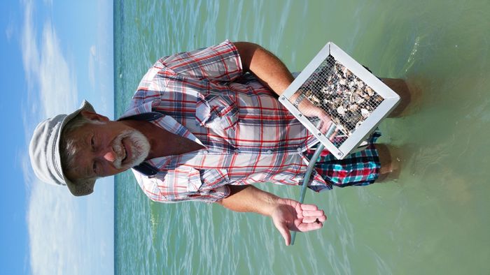 portrait-senior-man-holding-equipment-while-standing-sea-against-sky.jpg