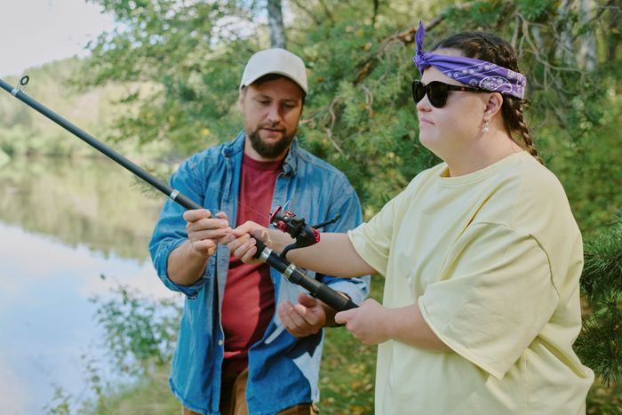 young-adult-man-teaching-girl-with-down-syndrome-fishing-outdoors.jpg