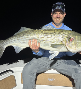 Reeling in a huge 37-inch striped bass as clouds roll in!