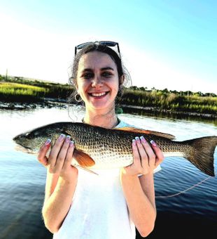 Smiling with a beautiful redfish catch on the water! 