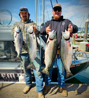 These anglers proudly show off a stellar salmon haul at the dock after a successful day out.