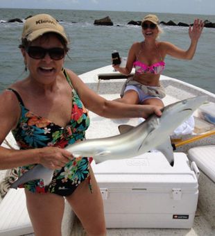 Woman holding shiny shark, smiling friend.