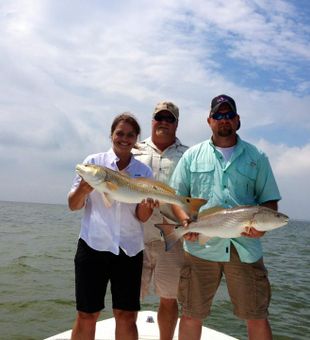 Three anglers with bright redfish.