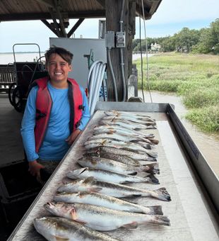 Smiling wide with a table full of speckled trout!