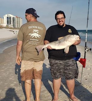 Smiling with a chunky red drum on the beach.