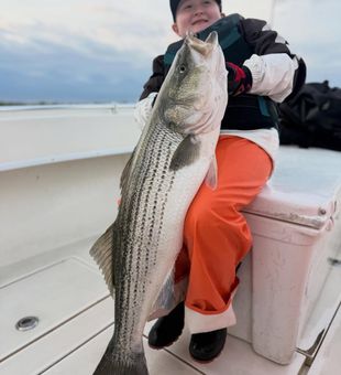 Impressive striped bass catch by young angler on a family fishing charter