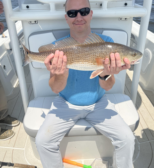 Reeling in a big redfish on a partly cloudy day with late afternoon rain.
