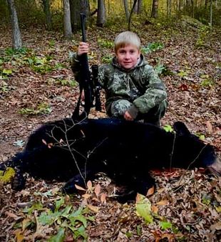 Confident young hunter with a majestic black bear.