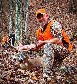 Massive whitetail buck down in crisp autumn woods.
