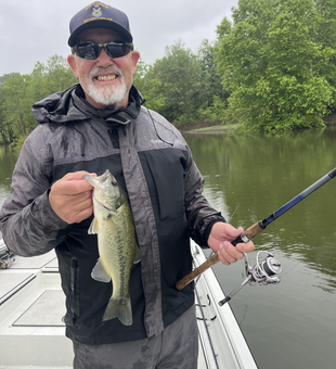 A trophy largemouth bass landed after a battle in the partly cloudy skies!