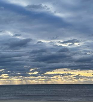 Dramatic skies meet calm seas.