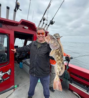Giant lingcod catch with beaming angler.