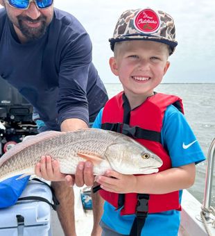 Proud young angler holding redfish on family fishing trip