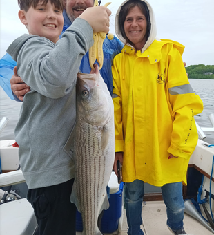 Happy anglers with a big striped bass catch!