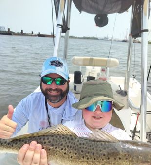 Young angler assisted by the Captain to get his big trout! 