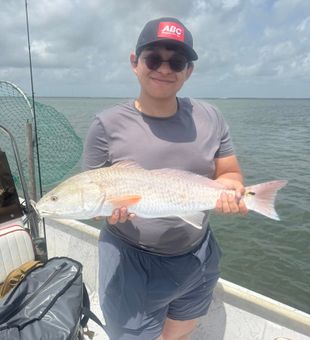 Bright catch of a hefty redfish on calm waters.