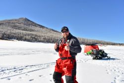 Ice fishing setup on frozen lake in Rifle Colorado with snowmobile and mountain backdrop