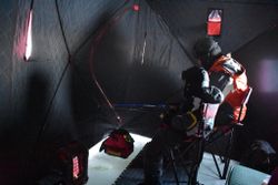 Ice fishing shelter interior with drilling equipment and gear setup in Rifle CO