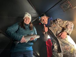 Two anglers displaying caught rainbow trout inside fishing shelter in Rifle Colorado