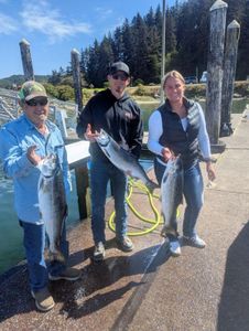 Three anglers displaying caught Coho salmon at fishing dock in Roseburg Oregon