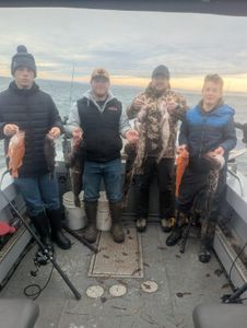 Four anglers display their catch of mixed fish species on fishing boat deck in Roseburg Oregon