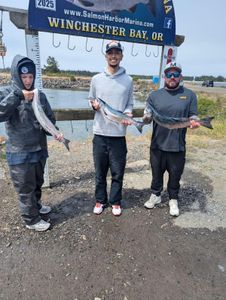 Three anglers displaying their fresh caught salmon at Winchester Bay OR fishing dock