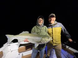 Two people fishing for striped bass in Wells